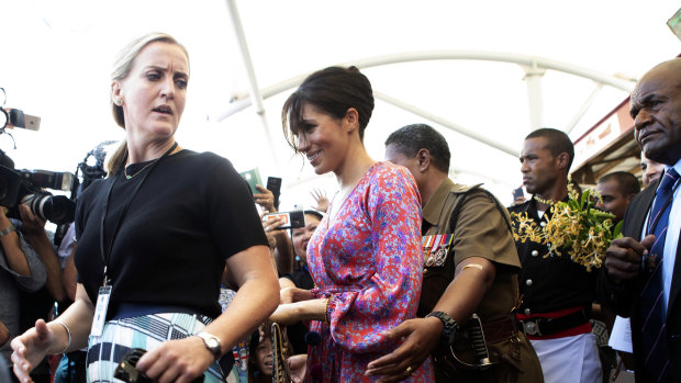 Meghan, Duchess of Sussex is escorted through a crowded market in Suva, Fiji.