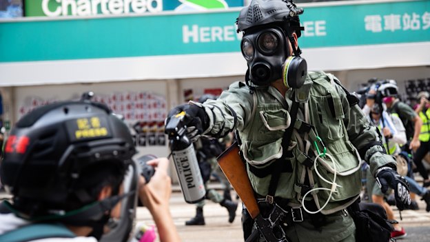 A riot police officer aims pepper spray at a journalist covering a protest in September 2019. 