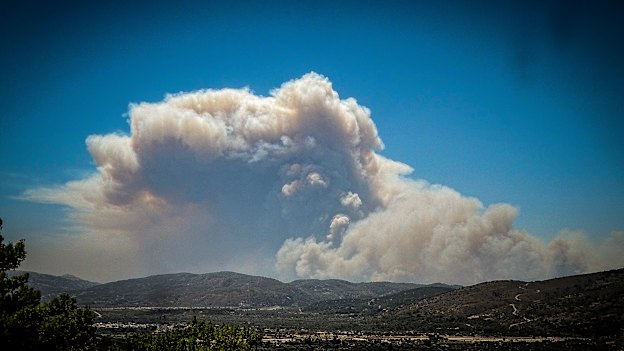 A cloud of smoke from a forest fire rises over the island of Rhodes, Greece.