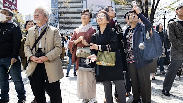 Pedestrians in Tokyo watch as the name of the new era is unveiled on April 1.