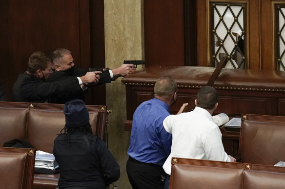 Capitol Police with guns drawn watch as protesters try to break into the House Chamber.