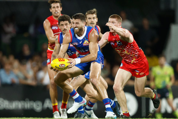 Marcus Bontempelli of the Bulldogs is tackled by Matt Rowell of the Suns.