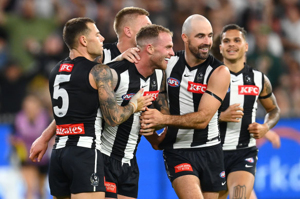 Tom Mitchell of the Magpies is congratulated by teammates after kicking a goal.
