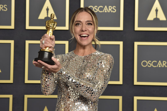 Sian Heder holds aloft her Oscar for best adapted screenplay for CODA.