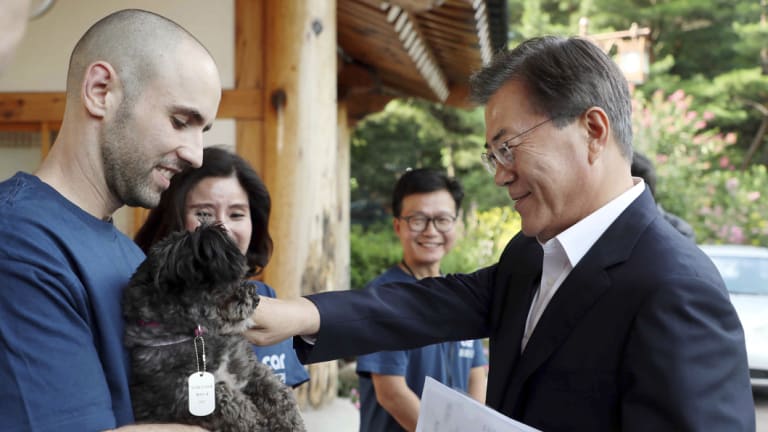 South Korean President Moon Jae-in, right, pats the dog named Tori at the presidential Blue House in Seoul.