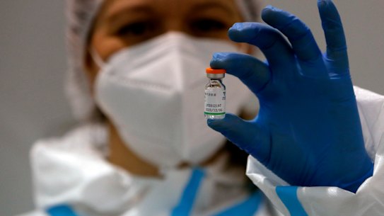 A medical worker poses with a vial of the Sinopharm’s COVID-19 vaccine.