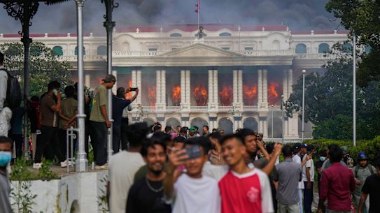 Protesters take selfies and celebrate at the Singha Durbar, the seat of the  Nepalese government’s various ministries and offices, after it was set on fire during the protests.