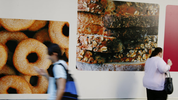 People walk past a doughnut billboard. Behavioural scientists have learnt it is often systems, and environments, that most influence a person's behaviour.