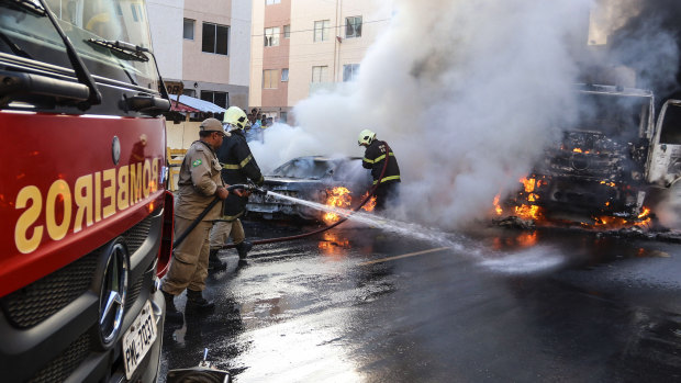 Firefighters put out torched vehicles on a street after attacks in the city of Fortaleza, north-eastern Brazil, on Thursday. Brazil's newly inaugurated government has ordered military police to Ceara state following a wave of attacks on banks, public buildings and infrastructure.