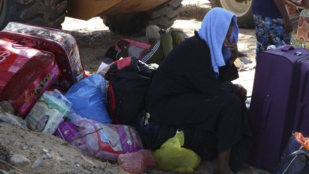 A migrant sits with his belongings as debris covers the ground after the airstrike at the detention centre.