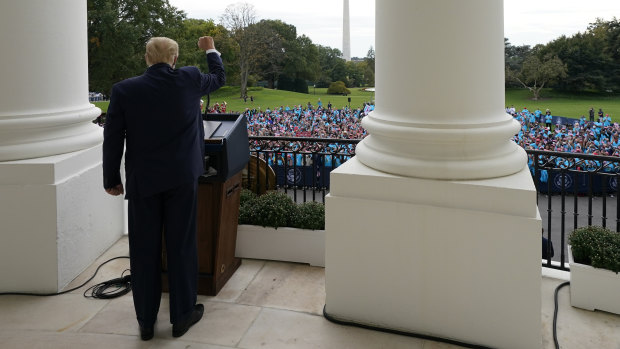 President Donald Trump gestures from the Blue Room Balcony of the White House.