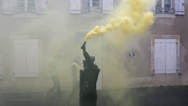 A protester holds a smoke grenade during a demonstration in Bourges, central France, on Saturday.