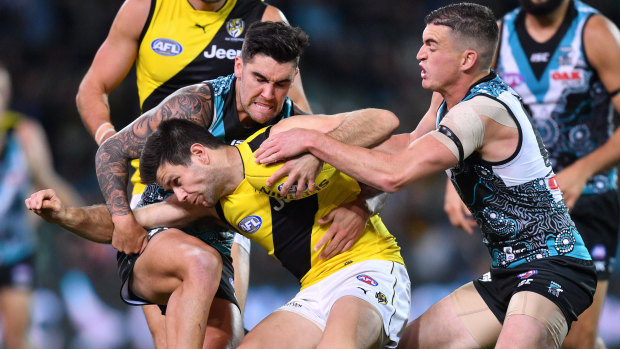 Trent Cotchin is wrapped up by Chad Wingard and Tom Rockliff.