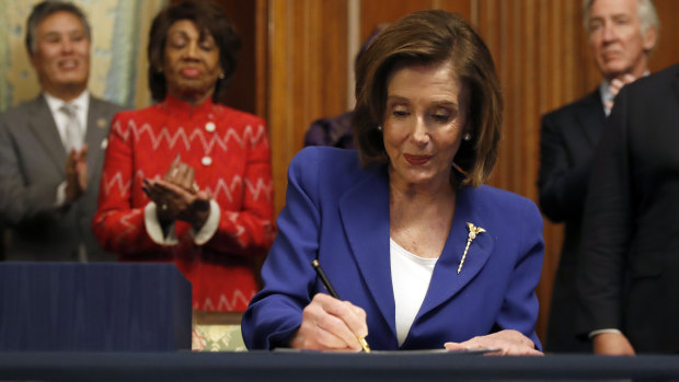 House Speaker Nancy Pelosi signs the Coronavirus Aid, Relief, and Economic Security Act (CARES).