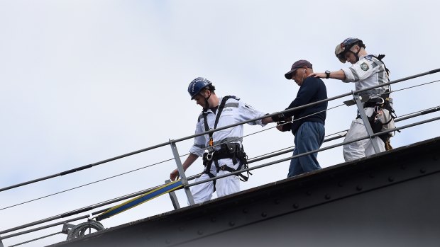 NSW police officers guide the man off the Sydney Harbour Bridge. 