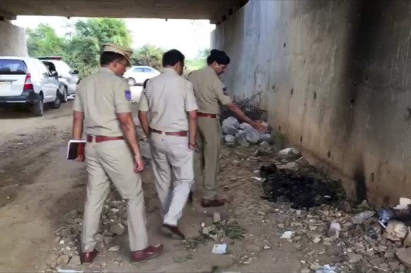 Indian police officers inspect the site where the woman's burned body was found.