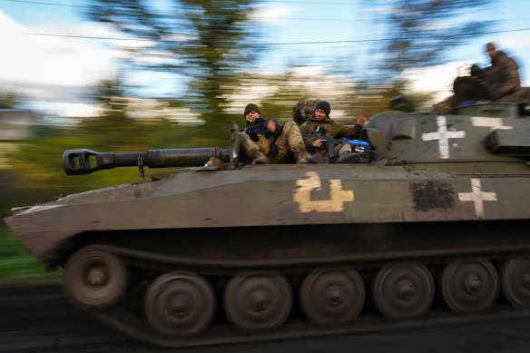 Ukrainian soldiers sit on an armoured vehicle as they drive on a road between Izium and Lyman in Ukraine.