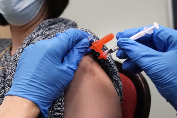 A woman receives a COVID-19 vaccine injection by a pharmacist at a clinic in Massachusetts.