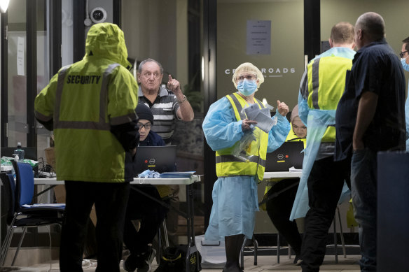 People get checked for coronavirus outside the Crossroads Hotel at Casula on Friday night.