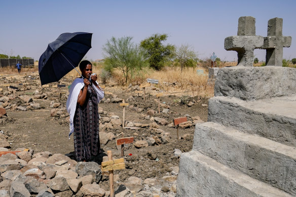 Agere Getnet weeps in front of a tomb containing the remains of her husband, Tebekaw, 37, hisbrother, Alie Abere, and his nephew, Aynew Mulat, among the mass graves at Abune Aregawi Ethiopian Orthodox Church.