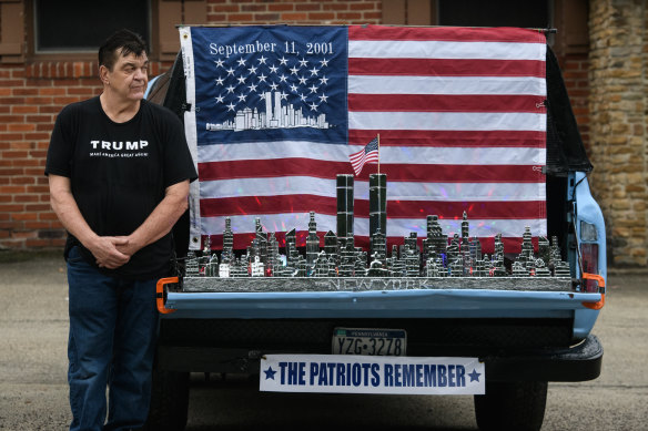 A supporter of President Donald Trump stands next to a 9/11 display on a truck along the Lincoln Highway in Stoystown, Pennsylvania, on Friday.