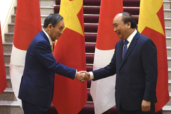 Japan's Prime Minister Yoshihide Suga, left, shakes hands with Vietnam's Prime Minister Nguyen Xuan Phuc after the exchange of documents in Hanoi on Monday.