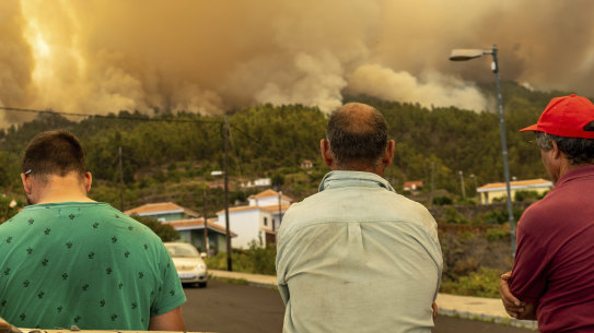 Residents look on at a burning forest fire on the Canary Island of La Palma.