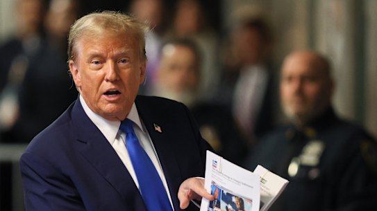 Former President Donald Trump speaks with the media while holding news clippings following his trial at Manhattan criminal court in New York on Thursday.