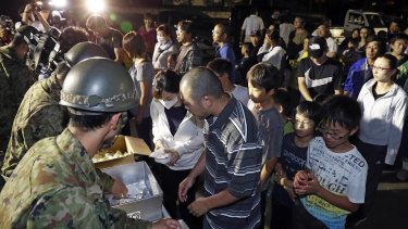 People wait to receive food at a shelter in Atsuma, Hokkaido, on Thursday night.