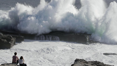 A couple watches waves hitting a coast of Shirahara town, Wakayama prefecture, central Japan.