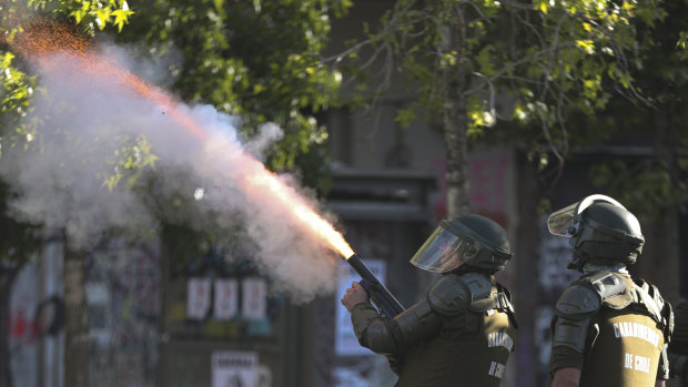 A police officer fires a tear gas canister at anti-government demonstrators during a protests in Santiago, Chile.