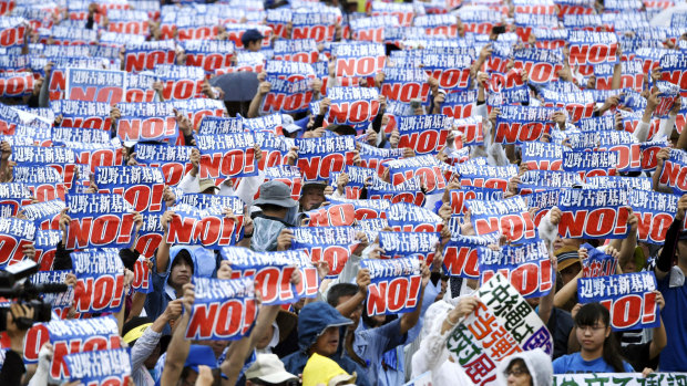 Protesters display signs against a planned US military base relocation during a rally in Naha, Okinawa prefecture, on the southern Japanese island on Saturday.