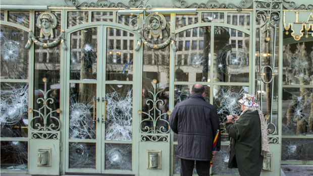 Bystanders take snapshots of the smashed windows of the famed tea salon Laduree on the Champs Elysees the day after it was vandalised during the 18th straight weekend of demonstrations by the yellow vests in Paris.
