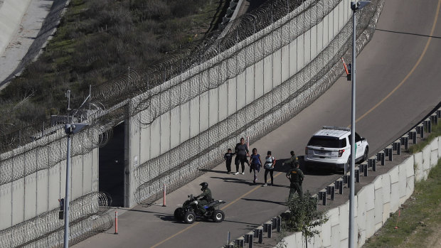Honduran asylum seekers are taken into custody by US Border Patrol agents after the group crossed the US border wall into San Diego, California. 