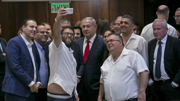 Knesset member Oren Hazan takes a selfie with Israel's Prime Minister Benjamin Netanyahu, centre, and MP David Bitan, right of Netanyahu, after a Knesset session that passed a contentious bill, in Jerusalem on Thursday.
