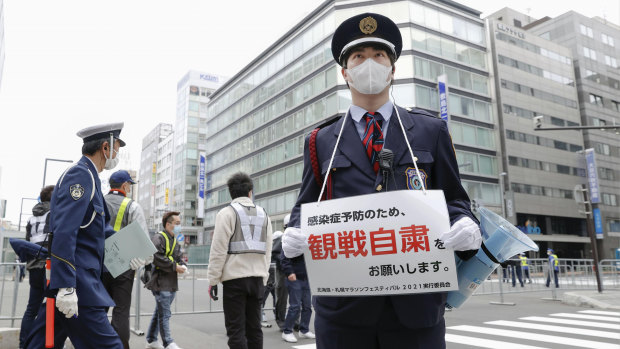 A security guard urges people not to watch a half-marathon in Sapporo in northern Japan on Wednesday to curb the spread of COVID-19.