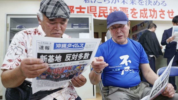 People take a look at a copy of a local newspaper reporting a referendum in Naha, Okinawa, Japan, on Sunday.