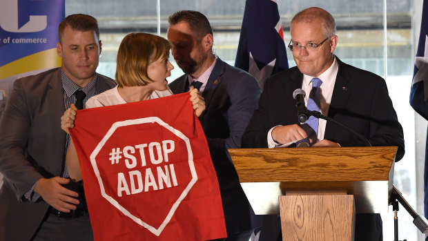 Not about to depart centre stage: An anti-Adani protester about to be led away after interrupting Prime Minister Scott Morrison's speech in Brisbane on Monday. 