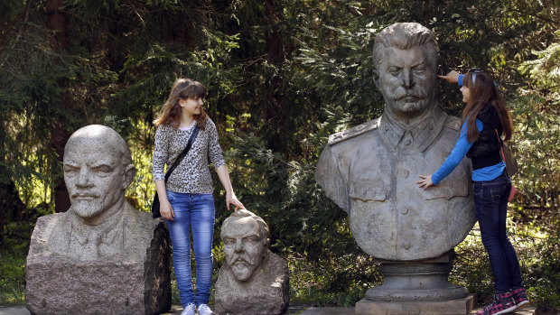 Girls joke around with statues of Soviet founder Vladimir Lenin, left, Felix Dzerzhinsky, centre, founder of the first Soviet secret police force and Soviet ruler Josef Stalin, right, at the Grutas Park in Druskininkai, Lithuania.