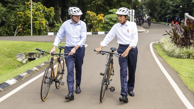 Anthony Albanese and  Joko Widodo push their bicycles after their ride.