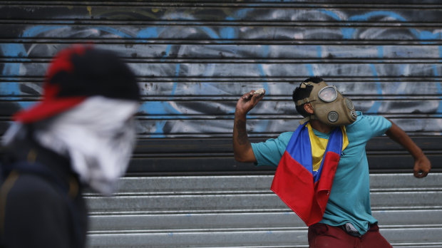 An anti-government protester winds up to throw a rock at security forces during clashes in Caracas.