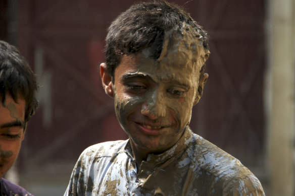 A boy covers his face with mud near his flood-hit home, in Charsadda, Pakistan.