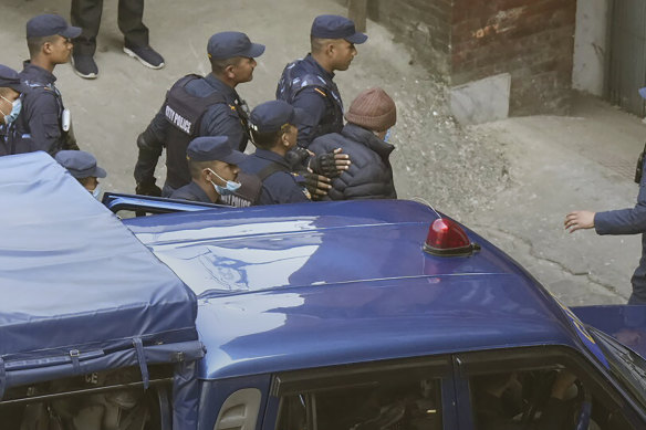 Nepalese police escort Charles Sobhraj, in brown cap, to the immigration office, in Kathmandu after his release.