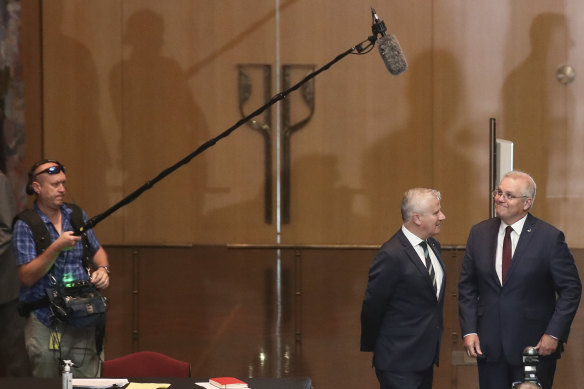 Michael McCormack in discussion with Scott Morrison as he spots a microphone above them.