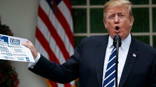 US President Donald Trump brandishes a fact sheet about the Mueller report at a surprise press conference in the White House Rose Garden. 