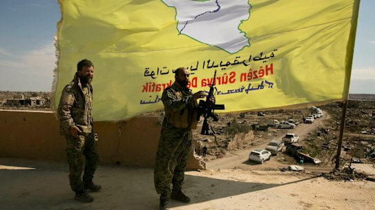 U.S.-backed Syrian Democratic Forces (SDF) fighters pose for a photo on a rooftop overlooking Baghouz, Syria, after the SDF declared the area free of Islamic State militants after months of fighting on Saturday, March 23, 2019. The elimination of the last Islamic State stronghold in Baghouz brings to a close a grueling final battle that stretched across several weeks and saw thousands of people flee the territory and surrender in desperation, and hundreds killed.  (AP Photo/Maya Alleruzzo)