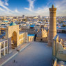 Aerial view down towards the famous Kalyan Poi Kalon Complex and Poi Kalon Minaret, Poi Kalan or Po-i-Kalyan and Mir Arab Madrasah (right side) in the center of the old town of Bukhara - Buxoro - Бухорo on a sunny day. Aerial Drone Point view at Sunset. Itchan Kala, Bukhara, Khorezm Region, Uzbekistan, Central Asia. 