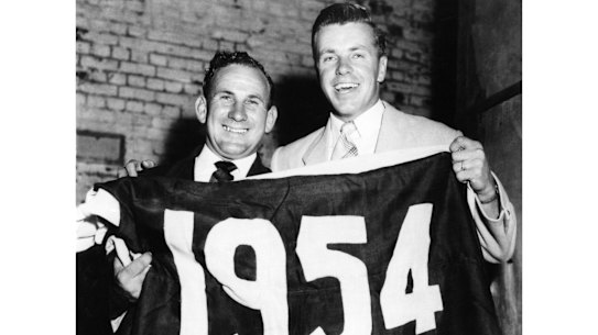 Footscray captain Charlie Sutton and teammate Ted Whitten hold the premiership flag.