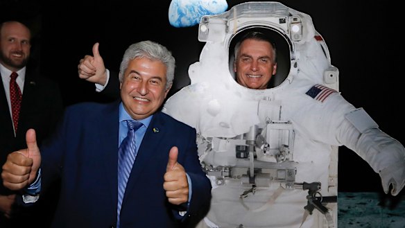 Brazilian Minister of Science and Technology Marcos Cesar Pontes, left, with President Jair Bolsonaro, standing behind a cardboard cutout of a US astronaut, at the US Embassy celebrating the 50th anniversary of the Apollo 11 moonwalk, in Brasilia, Brazil. 