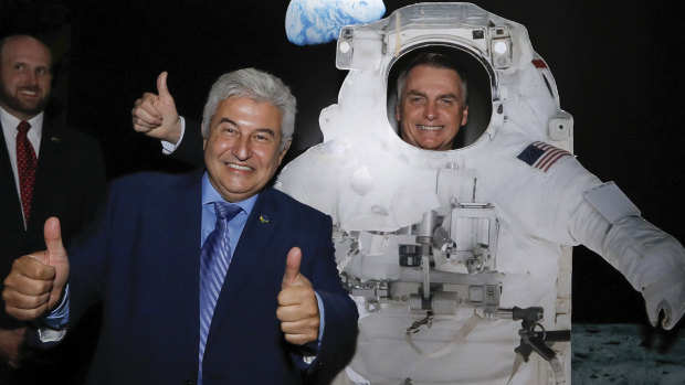 Brazilian Minister of Science and Technology Marcos Cesar Pontes, left, with President Jair Bolsonaro, standing behind a cardboard cutout of a US astronaut, at the US Embassy celebrating the 50th anniversary of the Apollo 11 moonwalk, in Brasilia, Brazil. 